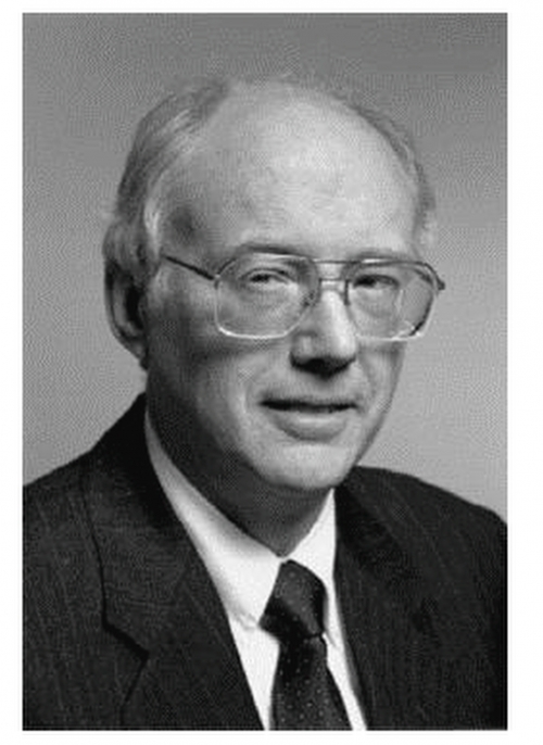 A black and white portrait of David Clark, an older man wearing glasses. 